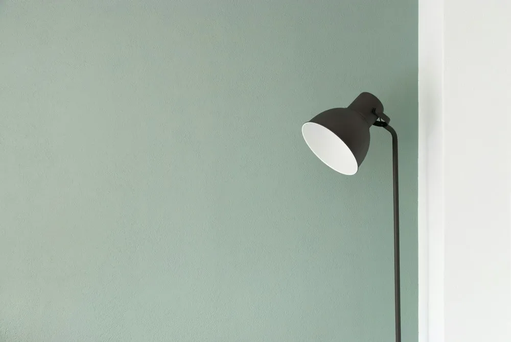 Lámpara de lectura junto a una pared de tono verde suave